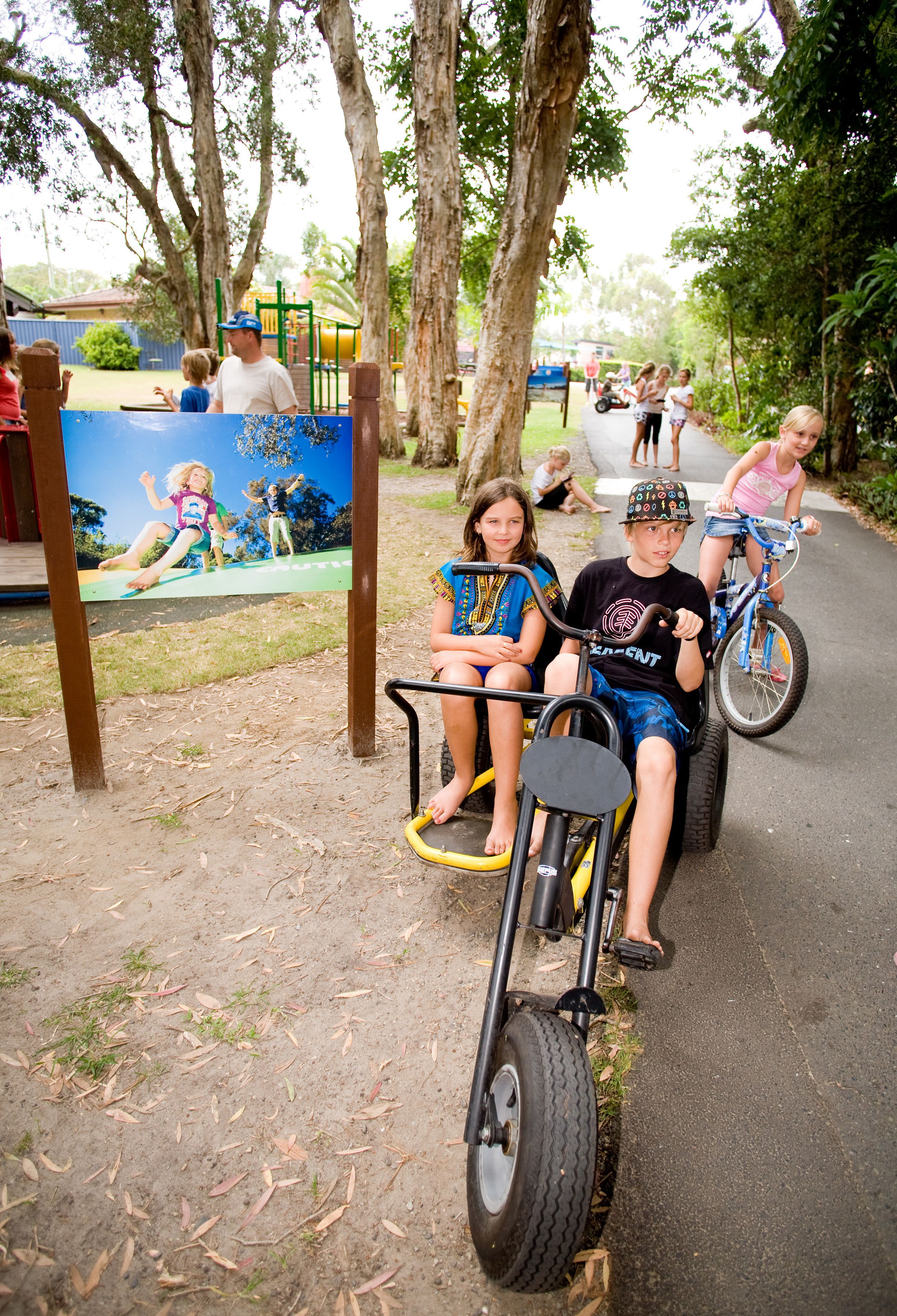 Un parque infantil con un sendero de tierra, árboles y un mural.