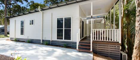 A single-story mobile home with a covered porch and a small front yard.