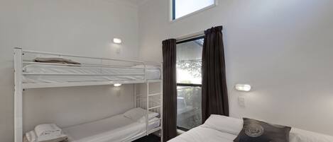 Une chambre avec un lit superposé, une fenêtre et un lit simple.