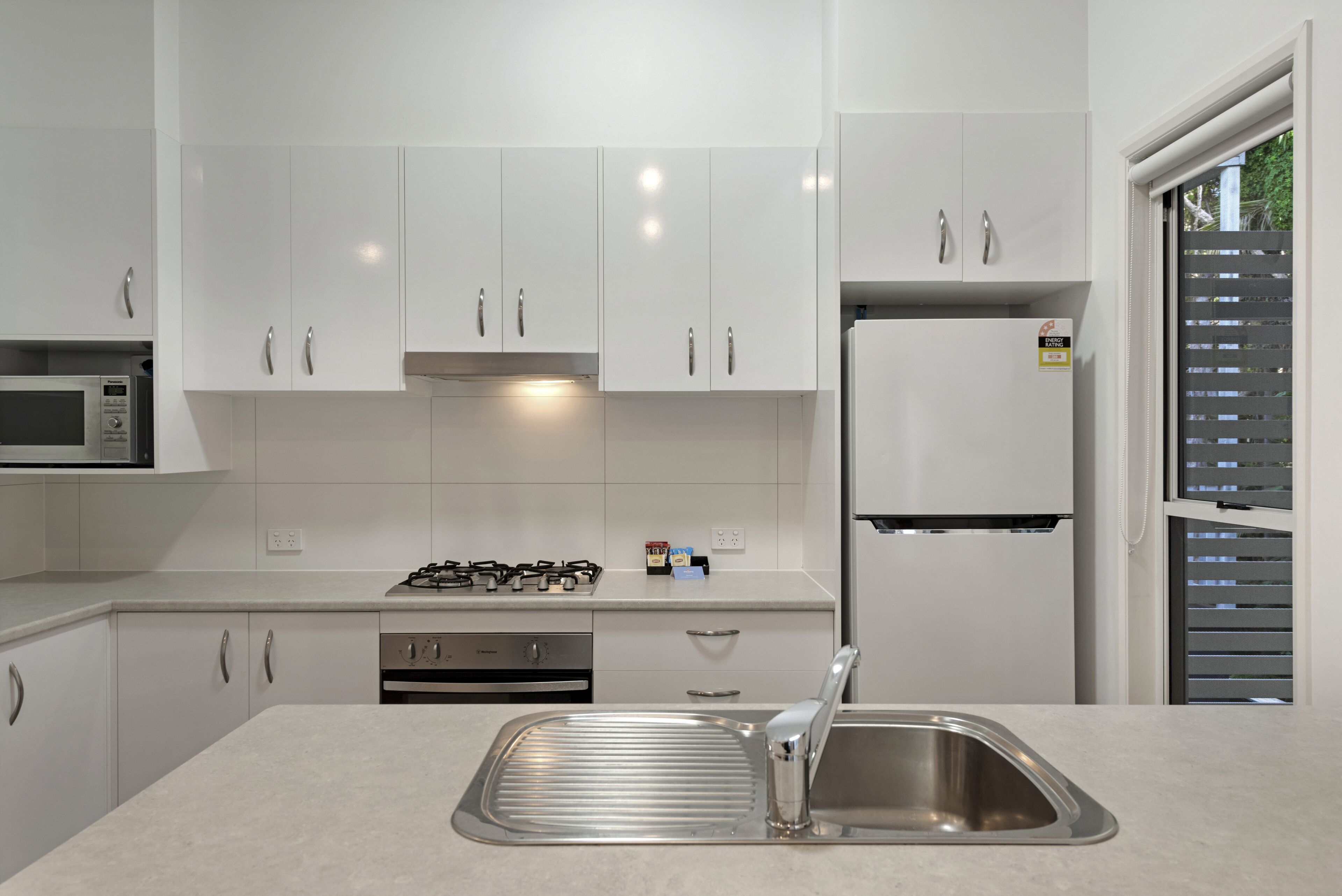 A modern kitchen with white cabinets, stainless steel appliances, and a built-in oven.