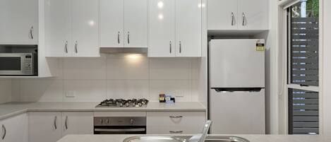 A modern kitchen with white cabinets, stainless steel appliances, and a built-in oven.