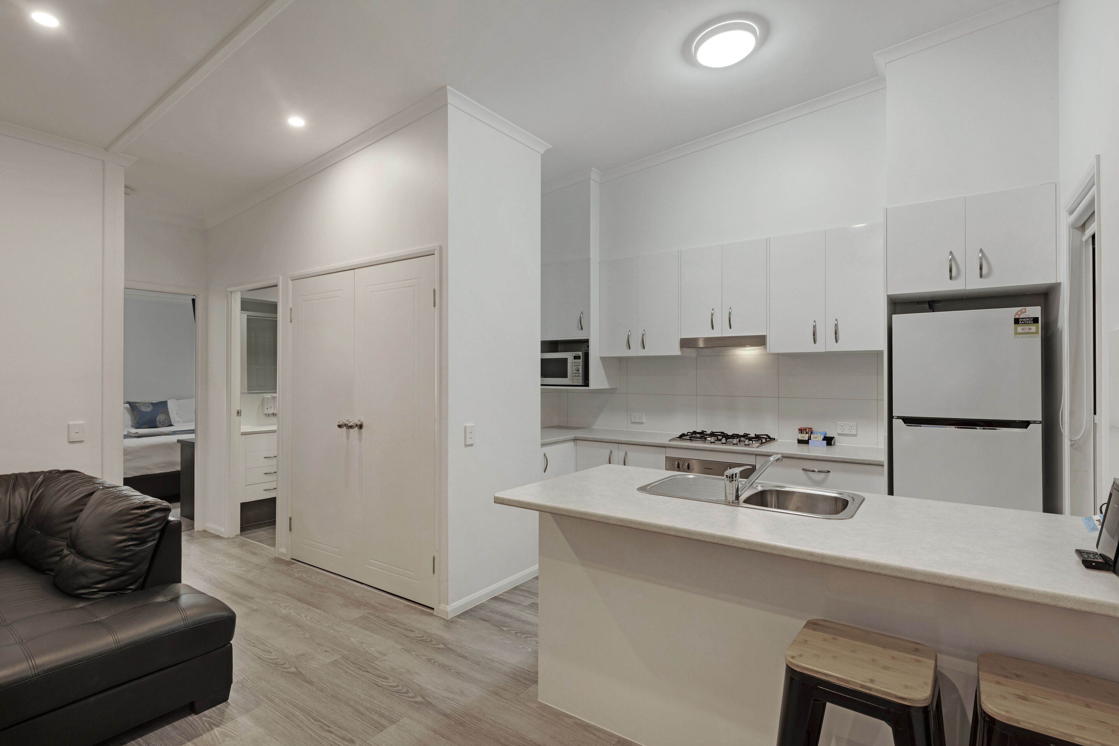 A modern kitchen with white cabinets, a central island with a sink, a stove, and a refrigerator.