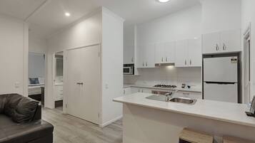 A modern kitchen with white cabinets, a central island with a sink, a stove, and a refrigerator.