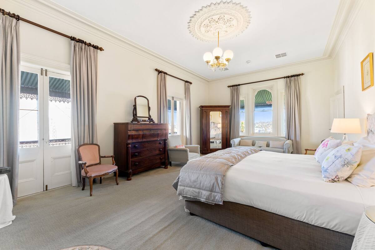 Un dormitorio con una cama grande, un aparador, una silla y un escritorio.