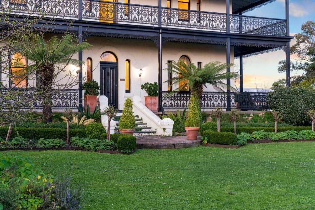 A two-story building with a balcony, a staircase, and a well-maintained garden.