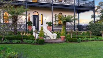 A two-story building with a balcony, a staircase, and a well-maintained garden.