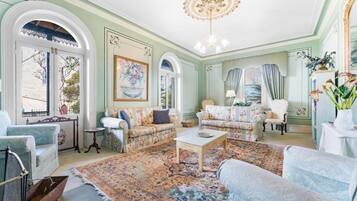A room with a large window, a chandelier, and a patterned rug.