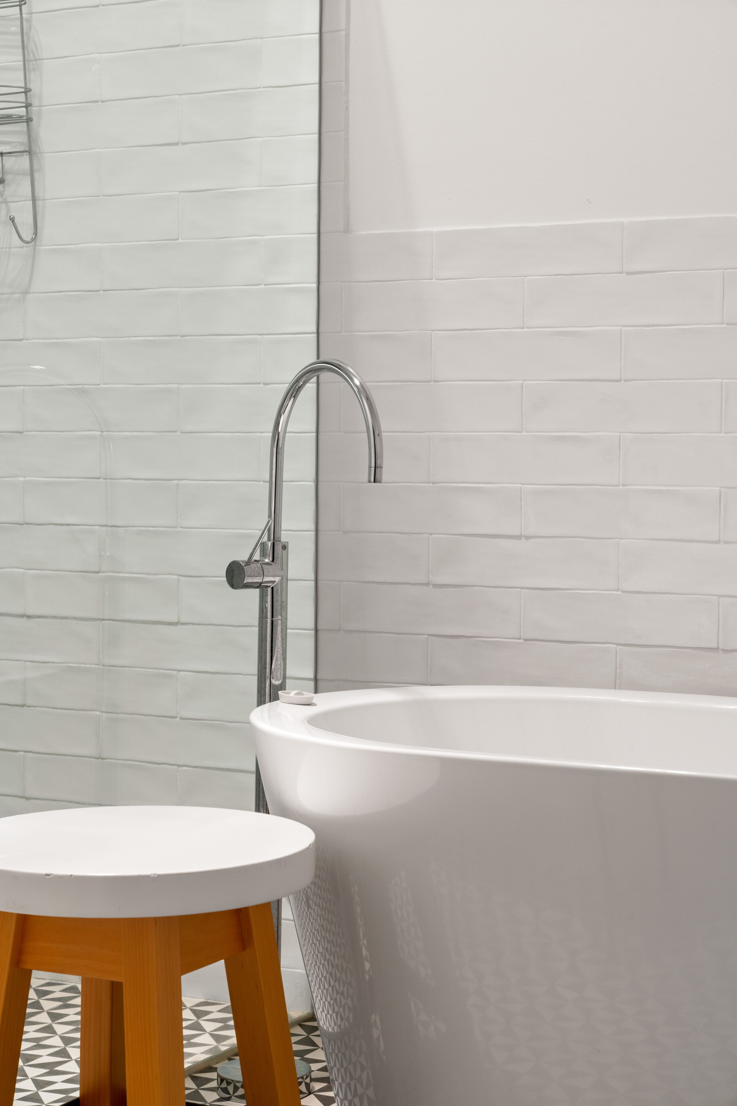 Une salle de bain moderne avec une baignoire sur pieds, un tabouret en bois et un espace douche.