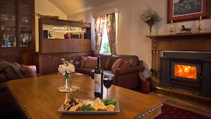A cozy living room with a wooden table set for a meal, a fireplace, and a bar area in the background. - The Racecourse Inn (Longford)
