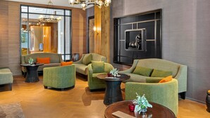 A modern lounge area with green upholstered sofas, a chandelier, and a wall-mounted horse sculpture. - The Gibraltar  (Bowral)