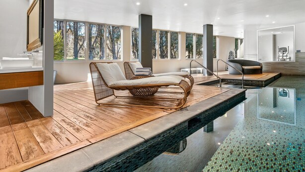 A modern spa area with wooden flooring, large windows, and wicker loungers. - The Gibraltar  (Bowral)
