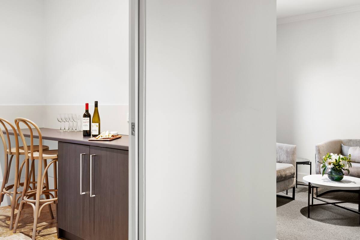 A modern kitchen with wooden chairs, a dining table, and a wine bottle.