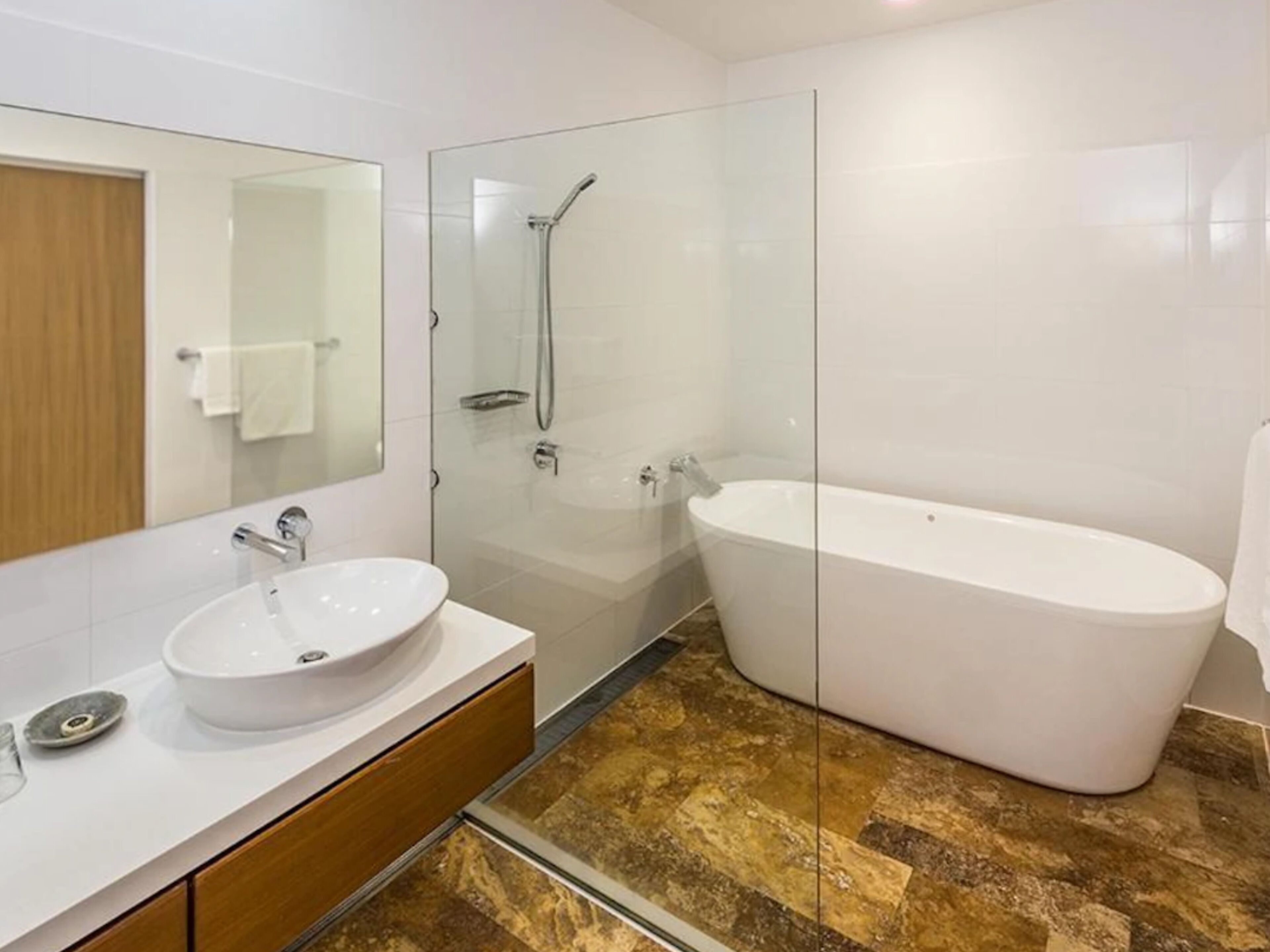A modern bathroom with a glass-enclosed shower, a freestanding bathtub, and a vanity with a sink.