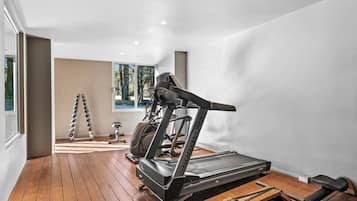 A home gym with a treadmill, stationary bike, and hex bar.