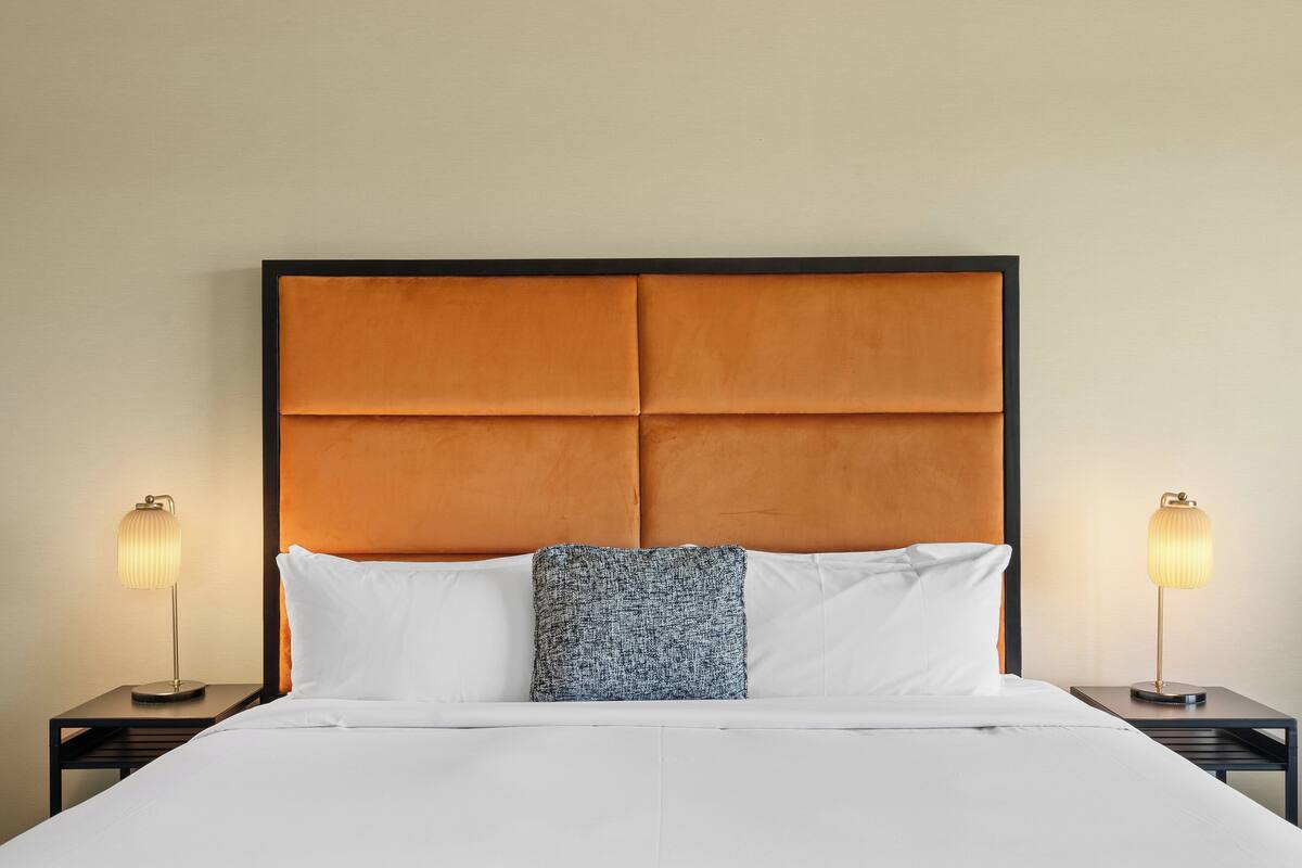 A hotel room with a large bed, two bedside tables, and a headboard.