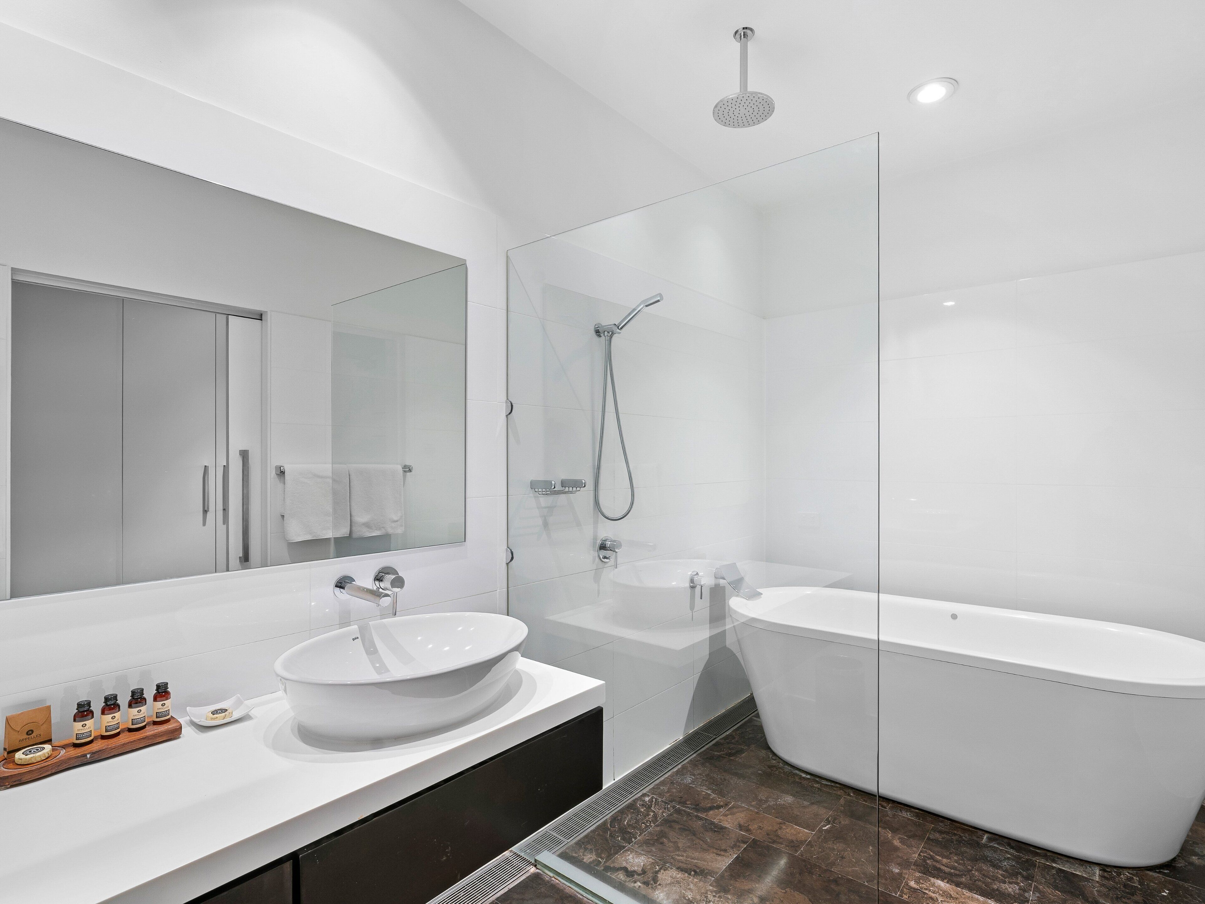 Un bagno moderno con una vasca freestanding, un grande specchio e una cabina doccia in vetro.