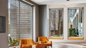 A spacious lobby with large windows, a wooden floor, and a seating area with cushioned chairs. - The Gibraltar  (Bowral)