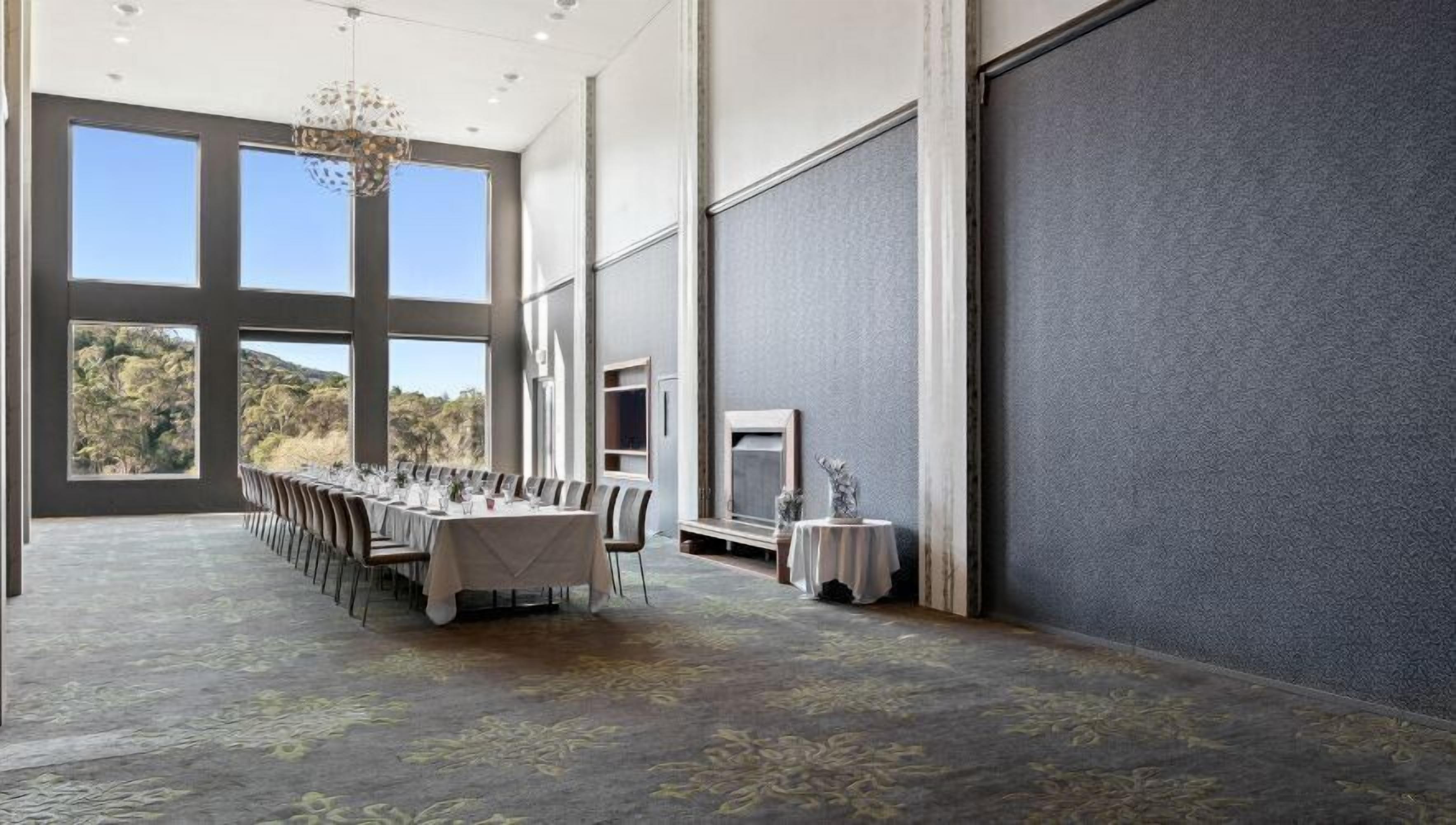 A large conference room with a long table set for a formal event, large windows, and a view of the outdoors.