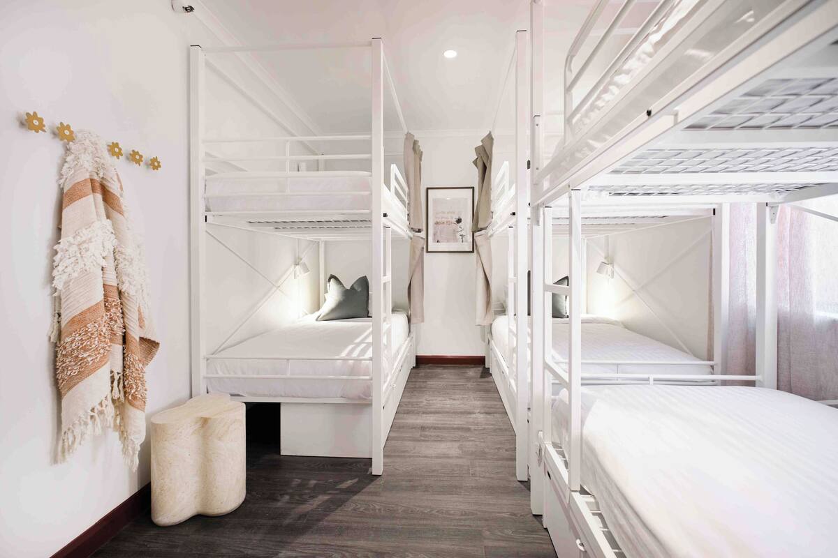 Een kamer met stapelbedden, een klein rond poef en een handdoekhouder aan de muur.