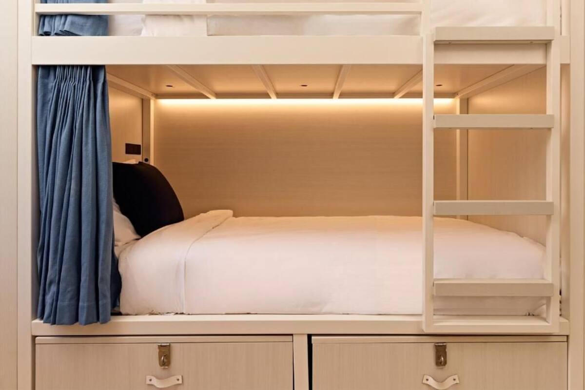 Een stapelbed met uittrekbaar bureau en lades, een hoofdbord en een gordijn.