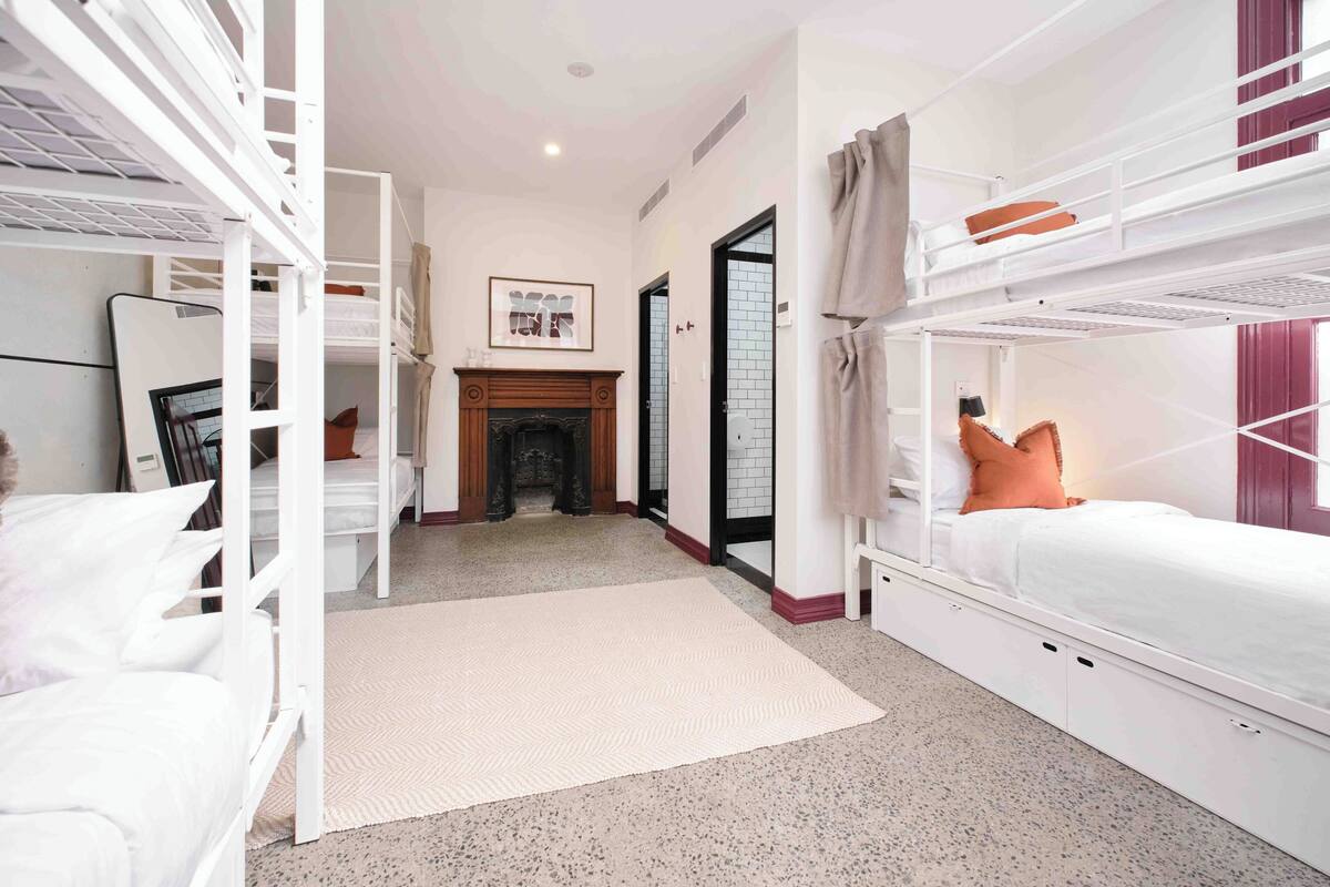 Een kamer met stapelbedden, een open haard en een lijst met een afbeelding aan de muur.