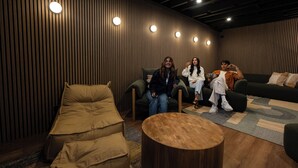 A modern lounge with a wooden slat wall, a round wooden coffee table, and a sofa. - Little Drifter Surry Hills (Redfern)