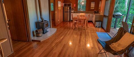 A spacious living area with a wooden floor, a dining table, and a comfortable seating area.