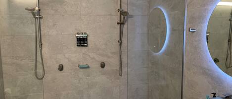 A modern bathroom with a glass-enclosed shower, a large mirror, and a marble sink.