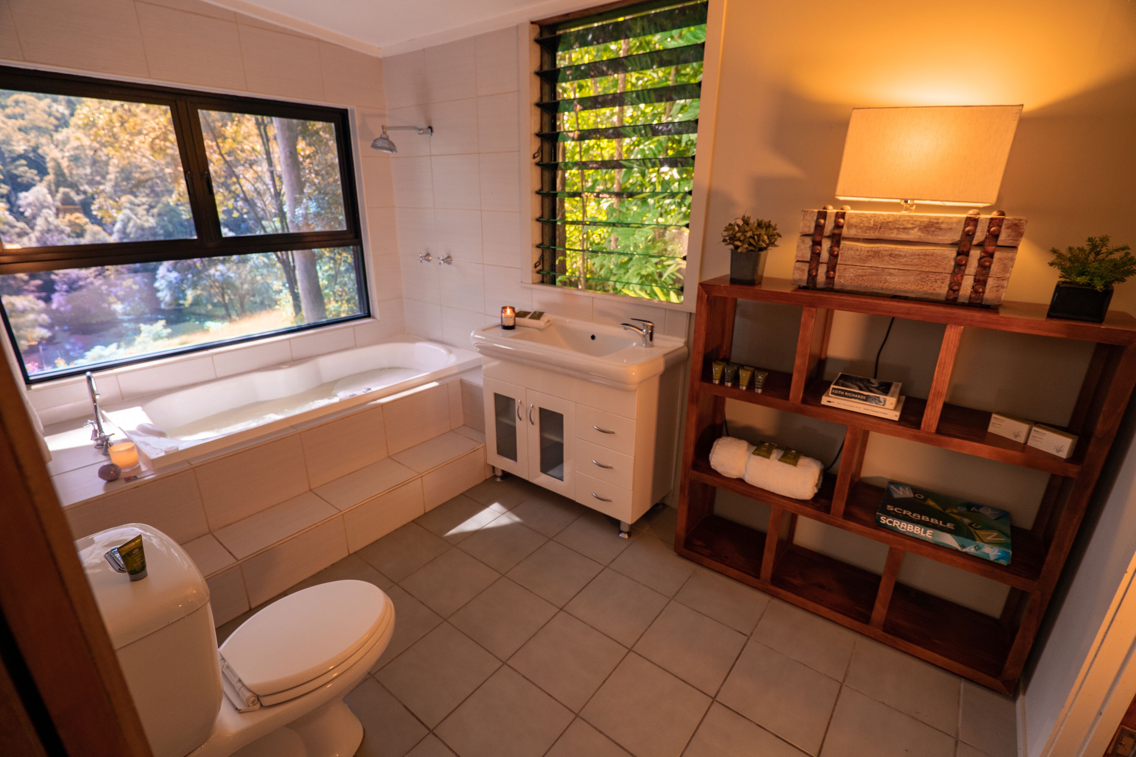A bathroom with a bathtub, toilet, sink, and a window with a view of trees.