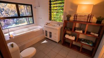 A bathroom with a bathtub, toilet, sink, and a window with a view of trees.