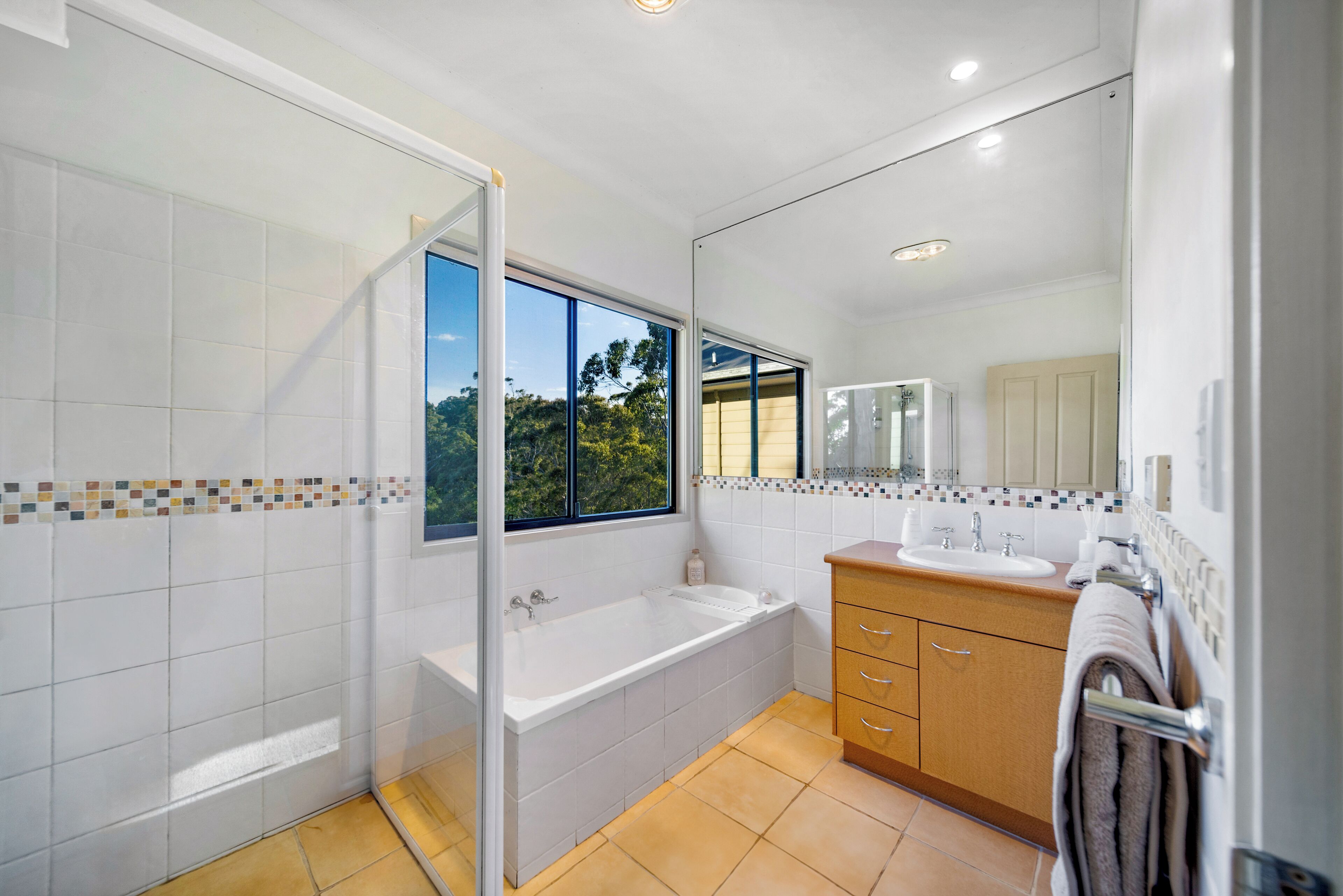 A modern bathroom with a bathtub, a shower, a sink, and a mirror.