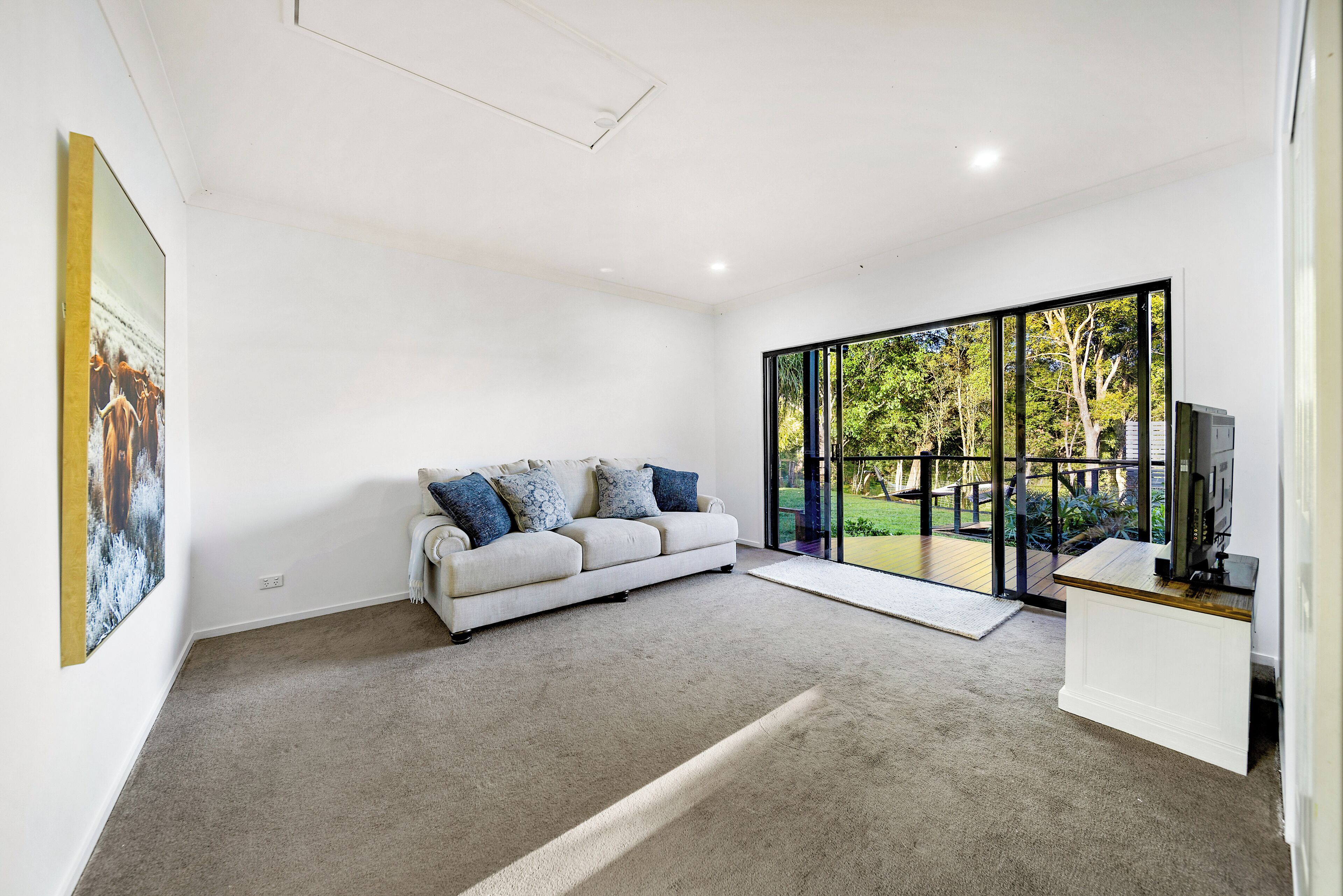 A modern living room with a large window, a sofa, and a flat-screen TV.