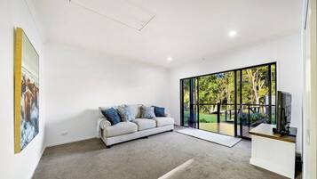 A modern living room with a large window, a sofa, and a flat-screen TV.