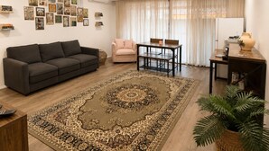 A living room with a sofa, a coffee table, a dining table, a ceiling fan, and a large rug. - Muswellbrook Motor Inn (Muswellbrook)