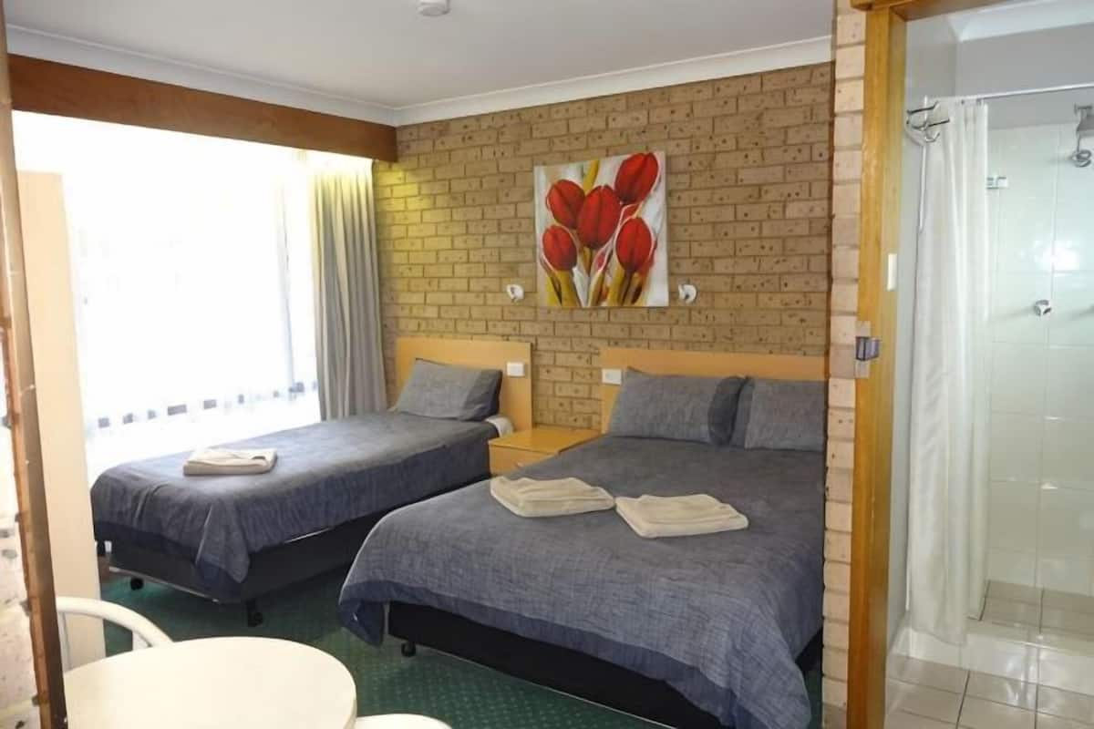 Ett hotellrum med två sängar, en dusch, en tavla med tulpaner och utsikt över omgivningarna.