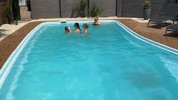 Alberca al aire libre, sombrillas en la alberca y camastros