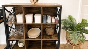 A wooden shelf unit with storage boxes, glassware, and decorative items. - Muswellbrook Motor Inn (Muswellbrook)