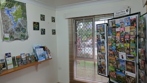 A room with a map on the wall, a bulletin board with travel brochures, and a window with blinds.