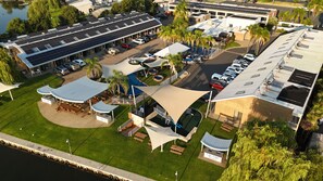 Vista aérea de un resort con piscina, mobiliario exterior y zona de estacionamiento.
