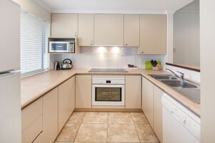A compact kitchen with a microwave, oven, dishwasher, and a sink.