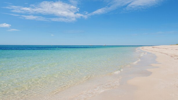 Una spiaggia con acque cristalline turchesi e una riva sabbiosa.