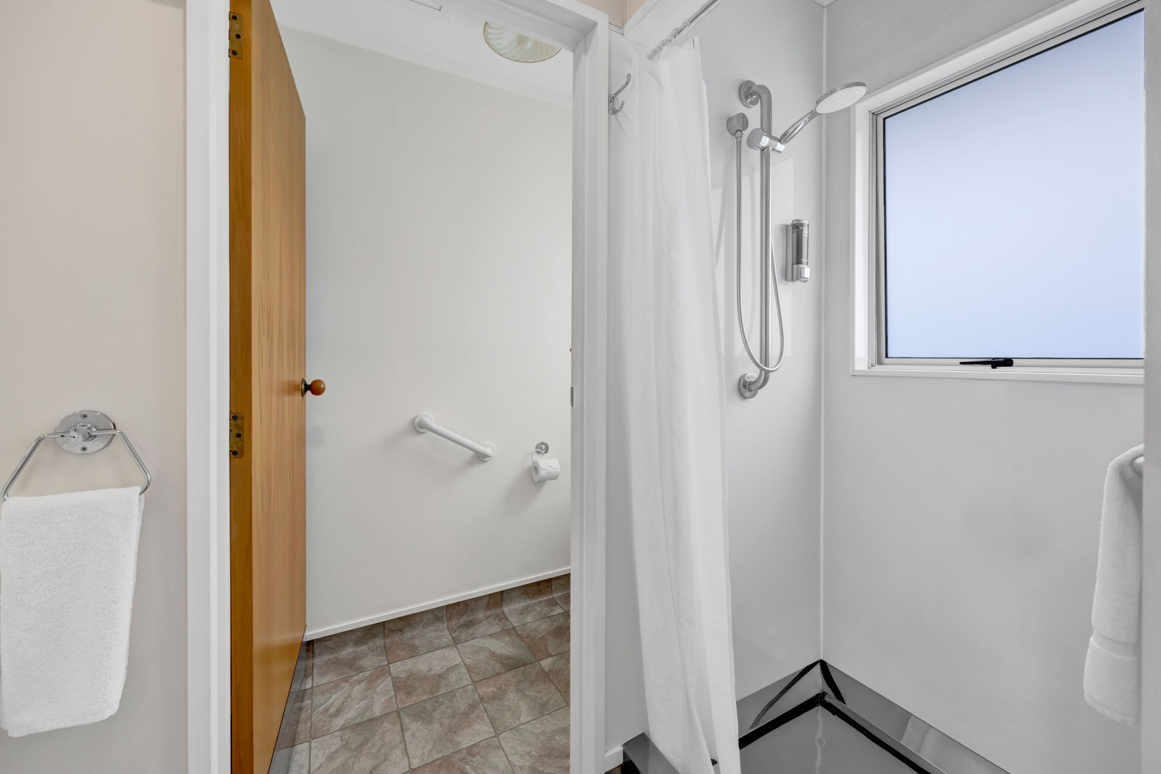 Une salle de bain moderne avec une douche, un porte-serviettes et une fenêtre.
