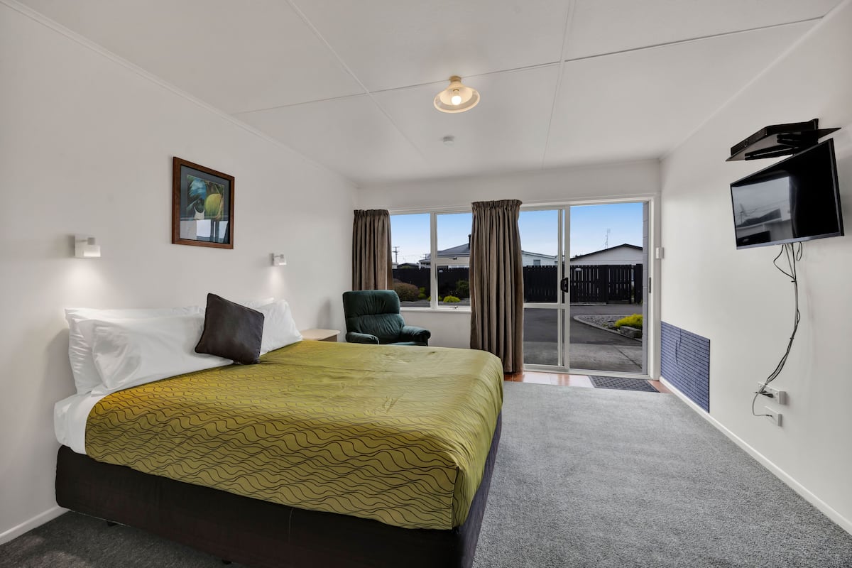 Une chambre d’hôtel avec un lit, une chaise, un téléviseur et une vue sur l’extérieur.