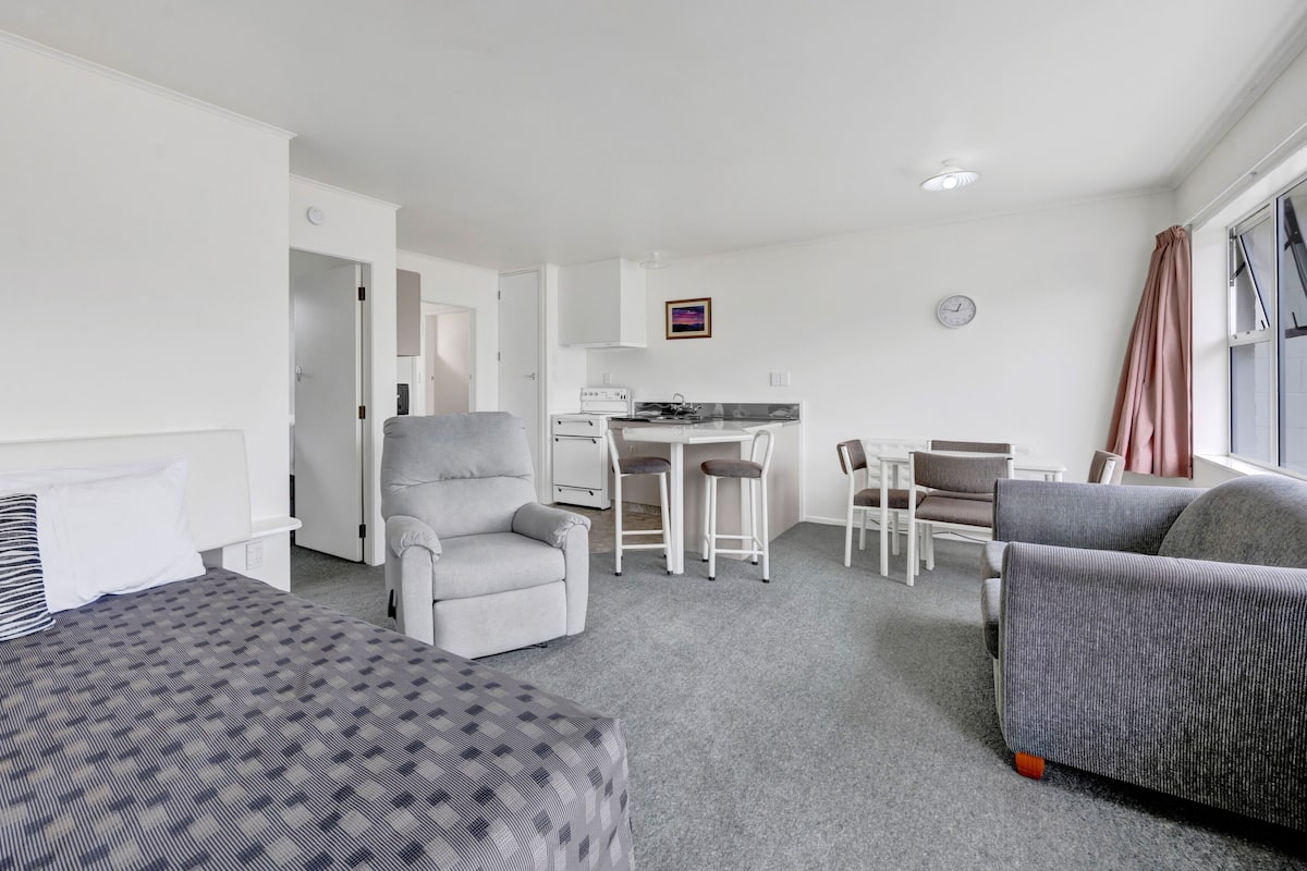 Une chambre d’hôtel avec deux lits, une kitchenette, un coin repas et un espace salon.
