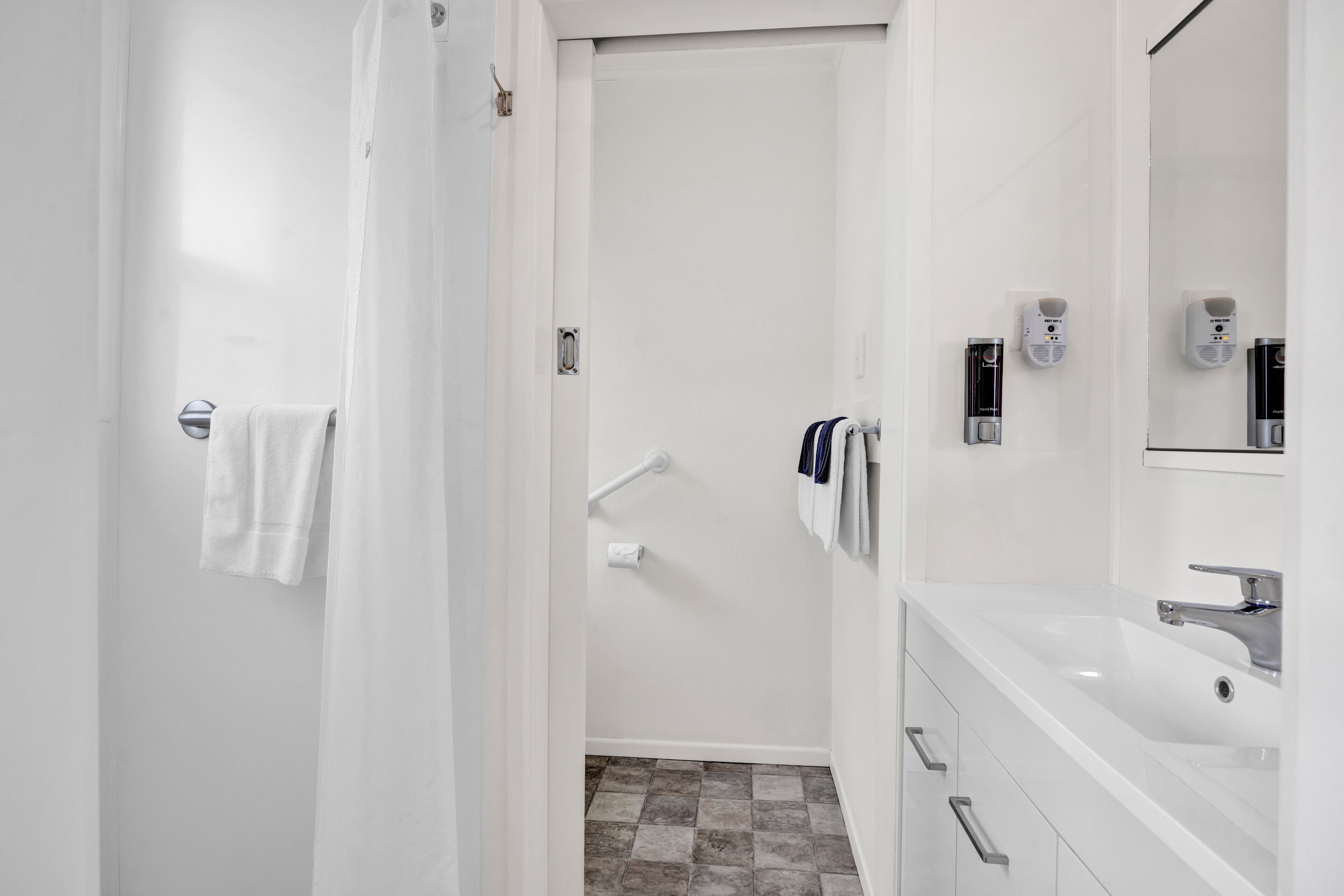 A modern bathroom with a white sink, mirror, and towel rack.