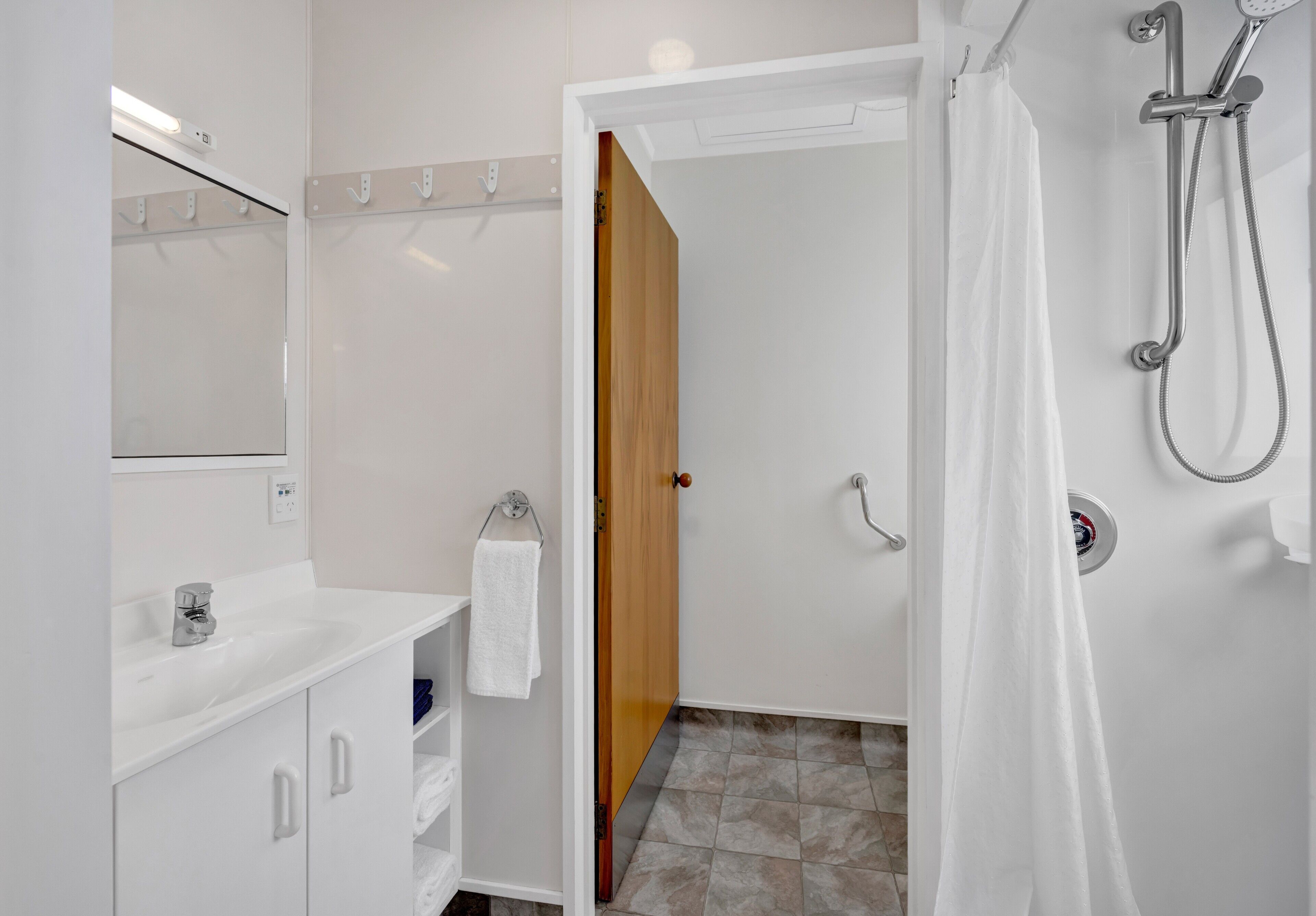 A modern bathroom with a white sink, mirror, and shower.