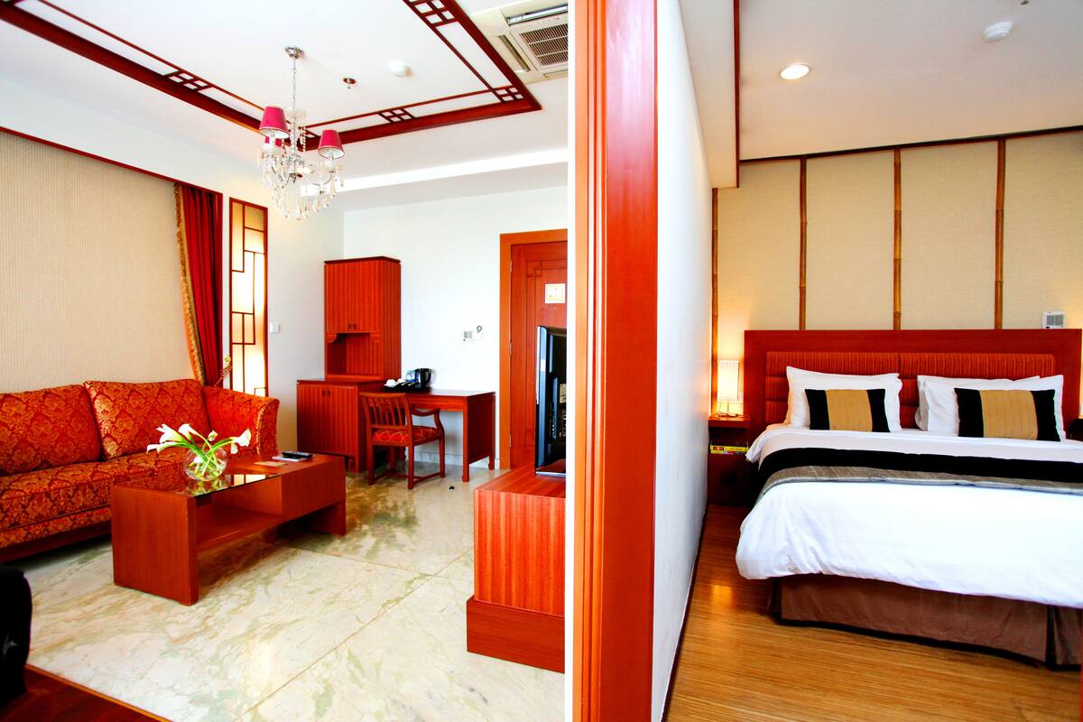 A hotel room with a sofa, a coffee table, a desk, and a bed.