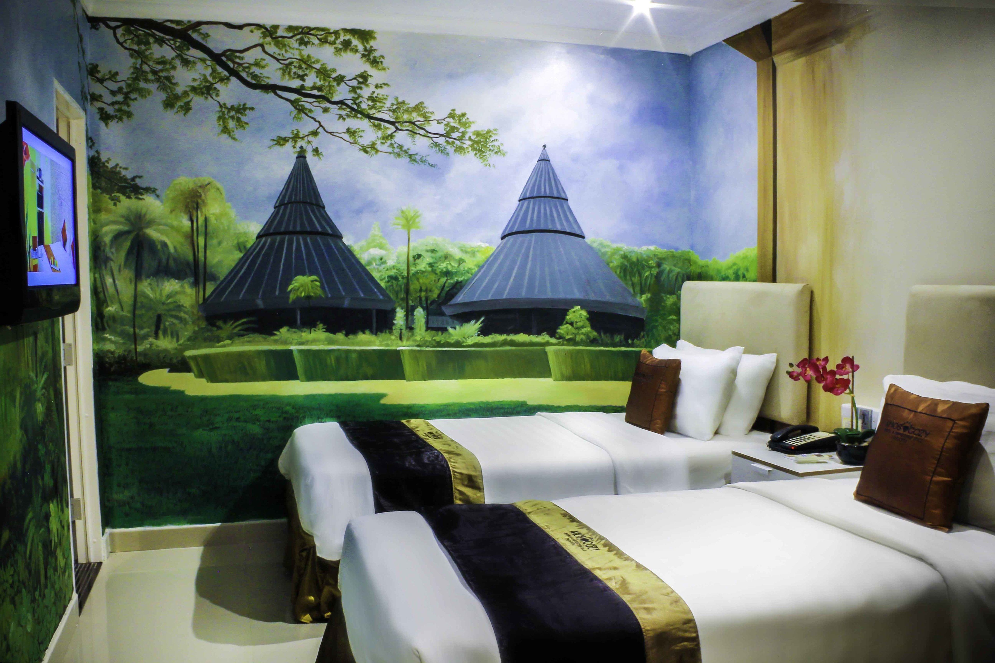 Une chambre d’hôtel avec deux lits, une télévision et une fresque représentant un paysage tropical.