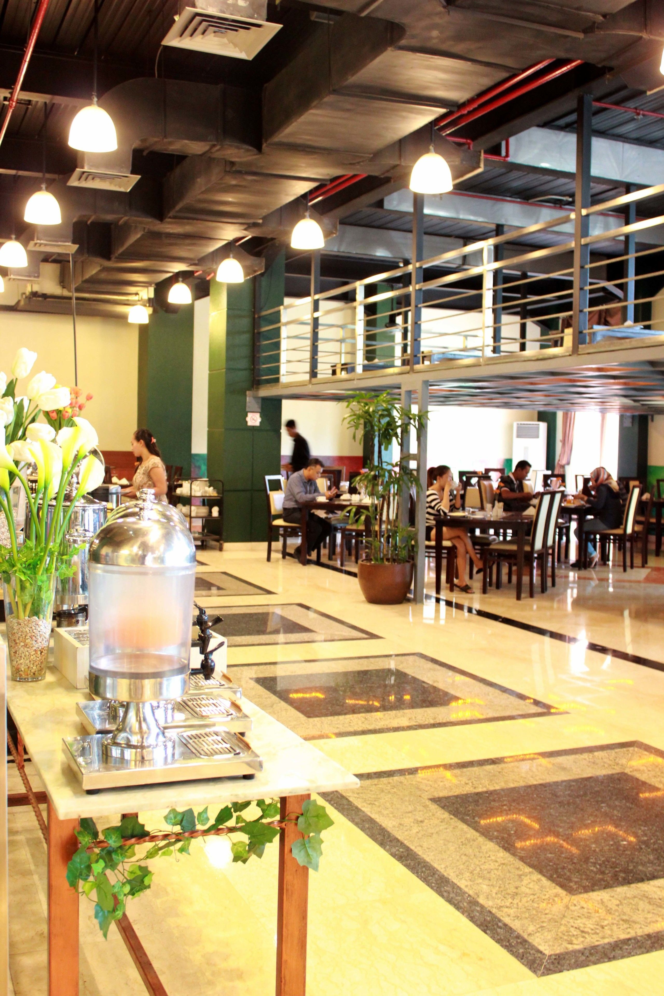 A spacious dining area with multiple tables and chairs, a buffet setup, and a potted plant.