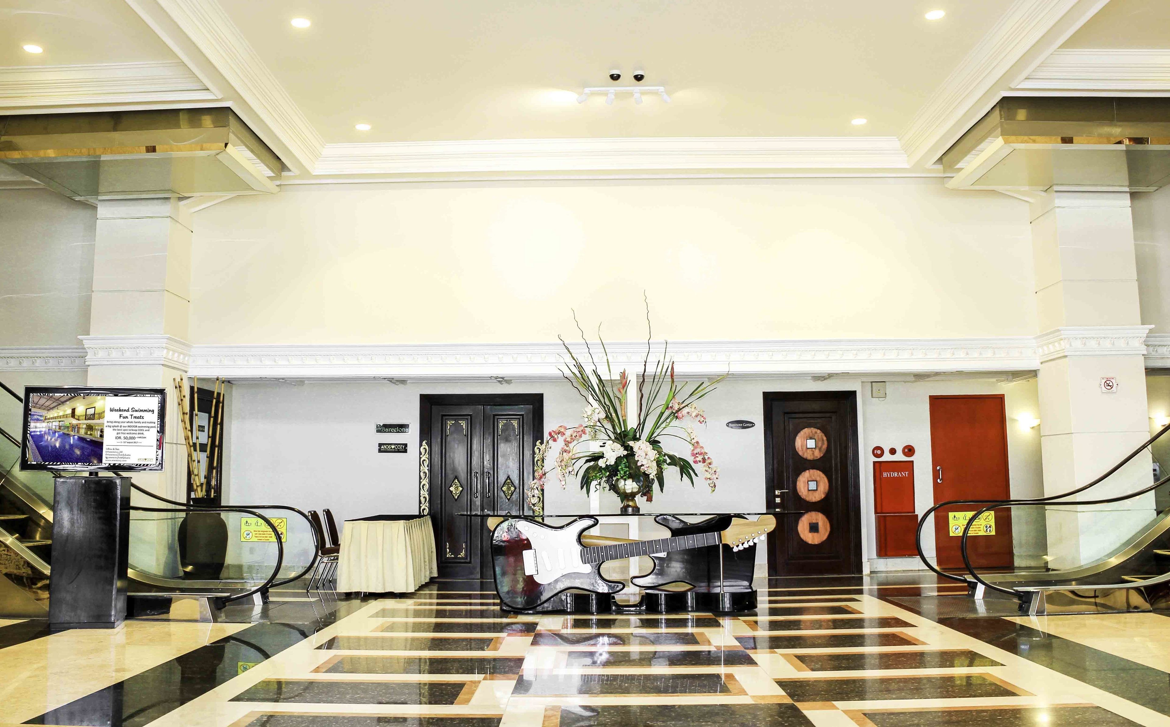 A hotel lobby with a check-in counter, a reception desk, and a large decorative plant.